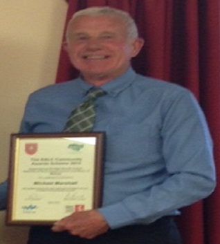 Michael Paul Marshall holding the British Empire Medal certificate he was awarded